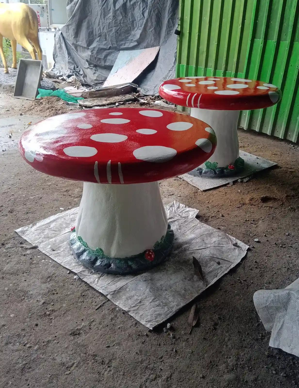 Bộ bàn ghế nấm xi măng đặt trong khuôn viên xưởng Bình An với tượng hươu vàng phía sau