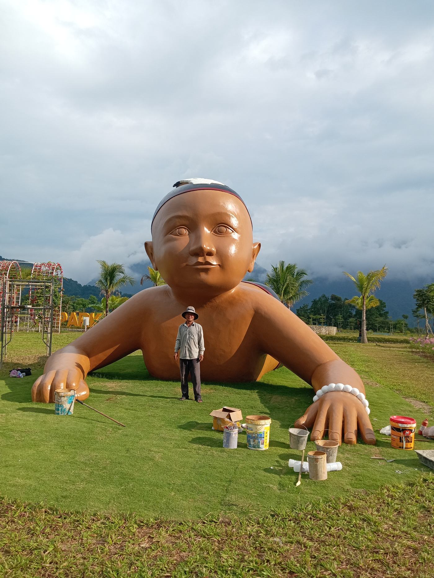 Nghệ nhân Trần Quang Hộ bên công trình tượng em bé khổng lồ trong giai đoạn hoàn thiện sơn màu